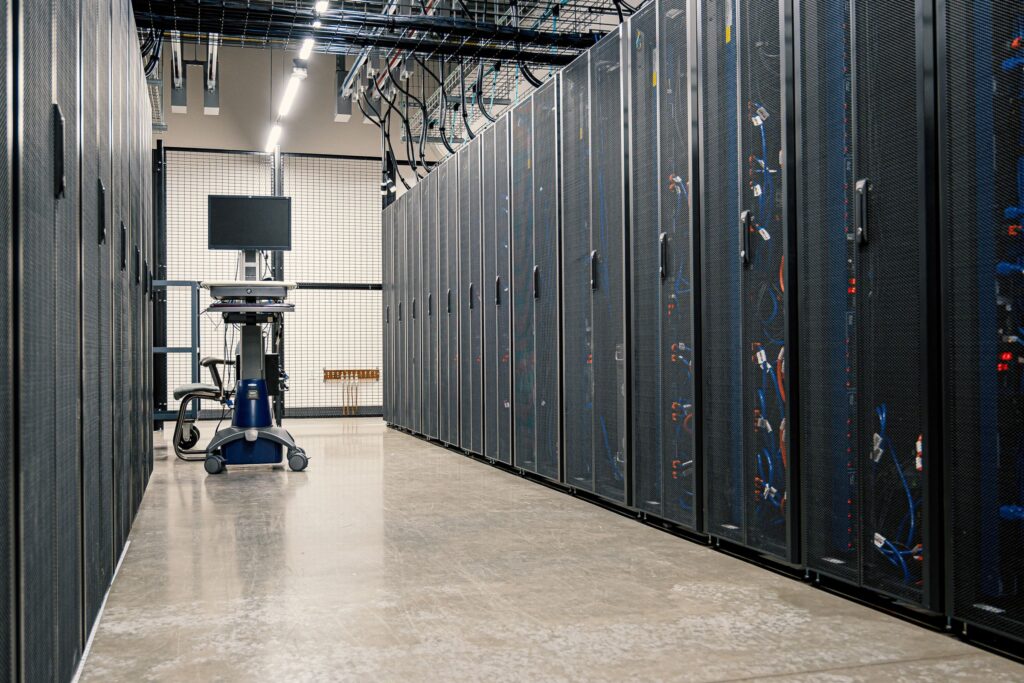Corredor de data center com fileiras de racks e eletrocalhas de cabeamento