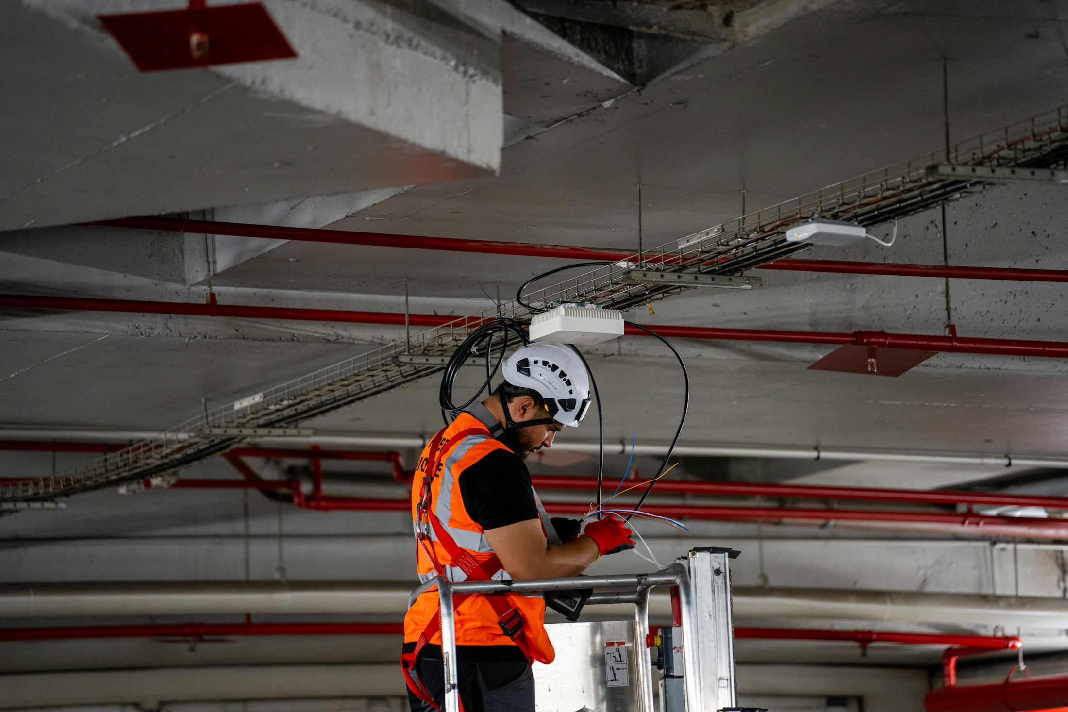 Técnico instalando equipamento de rede no teto de um galpão